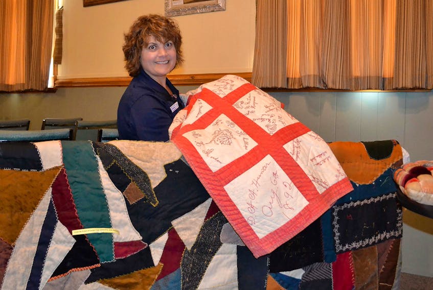 Isabel Delaney, visitor information guide at the Alberton Arts and Heritage Centre, displays a signature quilt made in 1892. Below it is a dark-patterned quilt from the George Gard estate which was donated to the Alberton Museum by Adele Heckman.
