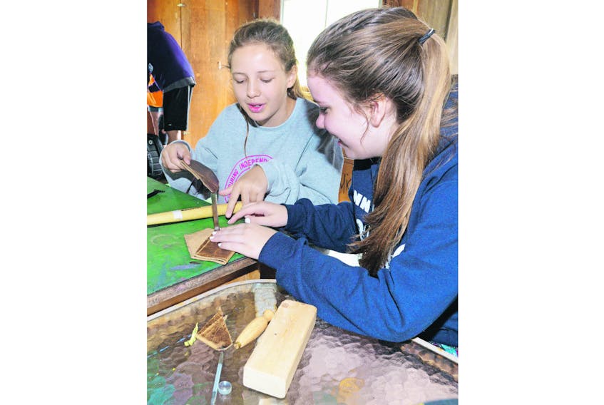 Lexi Edwards, left, and Abby Tutty, make wallets in their leather working class at Camp Red Fox in Canoe Cove in this file photo. Diabetes Canada has announced it is closing the diabetes camps in P.E.I. and New Brunswick and merging them with the camp in Nova Scotia.