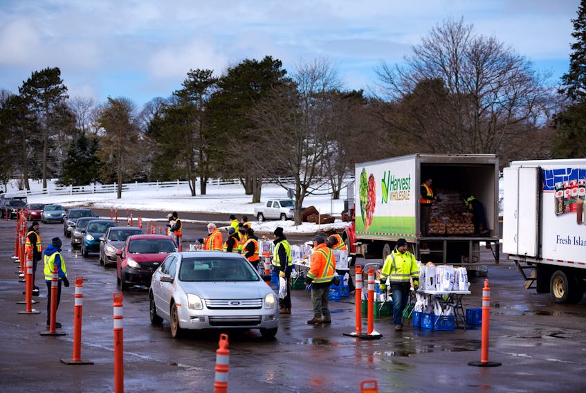 Cars line up Saturday by the P.E.I. Government Complex parking lot on Terry Fox Drive in Charlottetown to receive free care packages made up of dairy products and potatoes.
