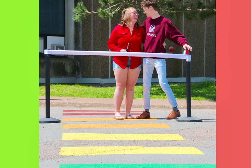 Tara Spicer and Jason Riemersma cut the ribbon for the official opening of the rainbow crosswalk on the Cobequid Educational Centre grounds Monday. Students painted the crosswalk, which goes from the school to Colchester Legion Stadium.