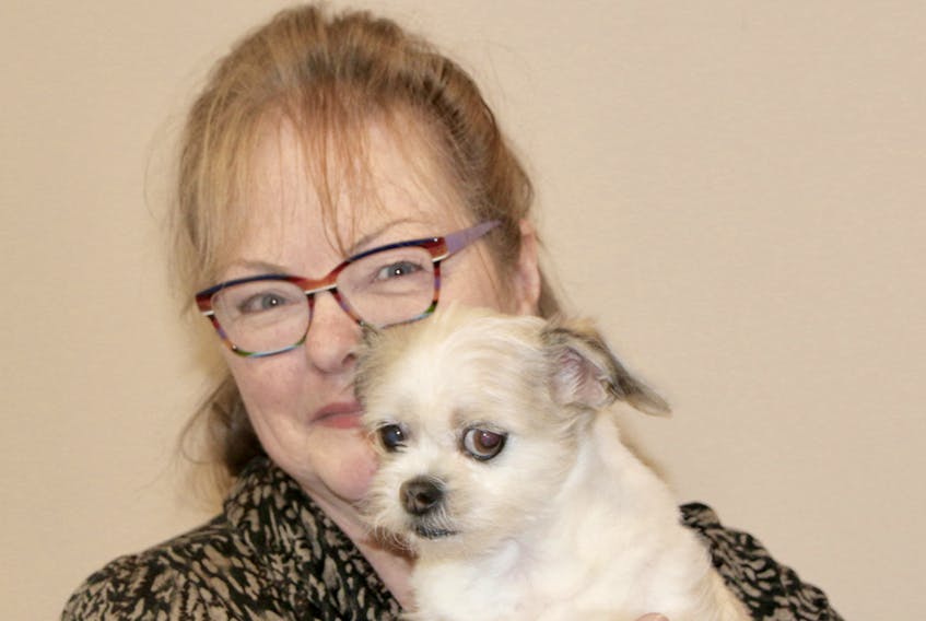 Shelly Canfield holds Sasha, her mother's dog. Shelly's love of dogs led her to becoming a groomer and opening her own business.