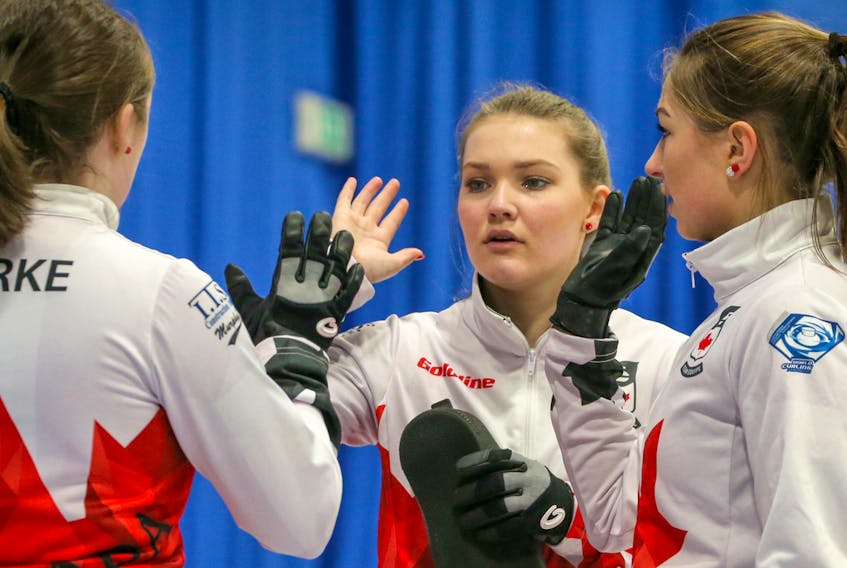 Lindsey Burgess, middle, and her cousin Karleee, right exchange high fives with teammates during action at the world junior women's curling championship. Richard Grey/World Curling Federation