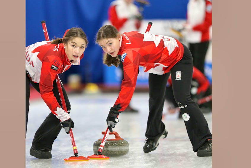 Karlee, left, and Lindsey Burgess sweep during action against Switzerland on Wednesday at the world junior women's curling championship. Richard Gray/World Curling Federation