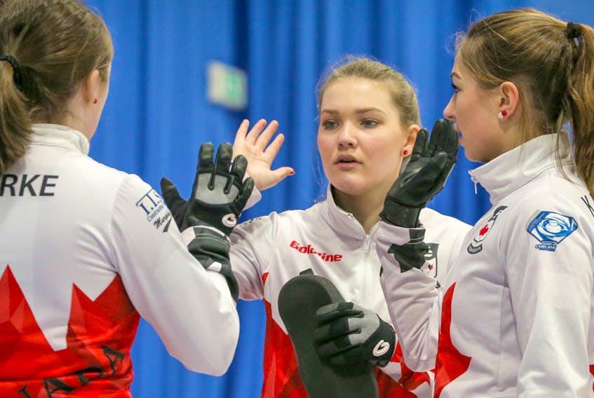 Lindsey Burgess, middle, and her cousin Karlee, right, exchange high-fives with their teammates during action this week at the world junior women's curling championship in Aberdeen, Scotland. Richard Gray/World Curling Federation