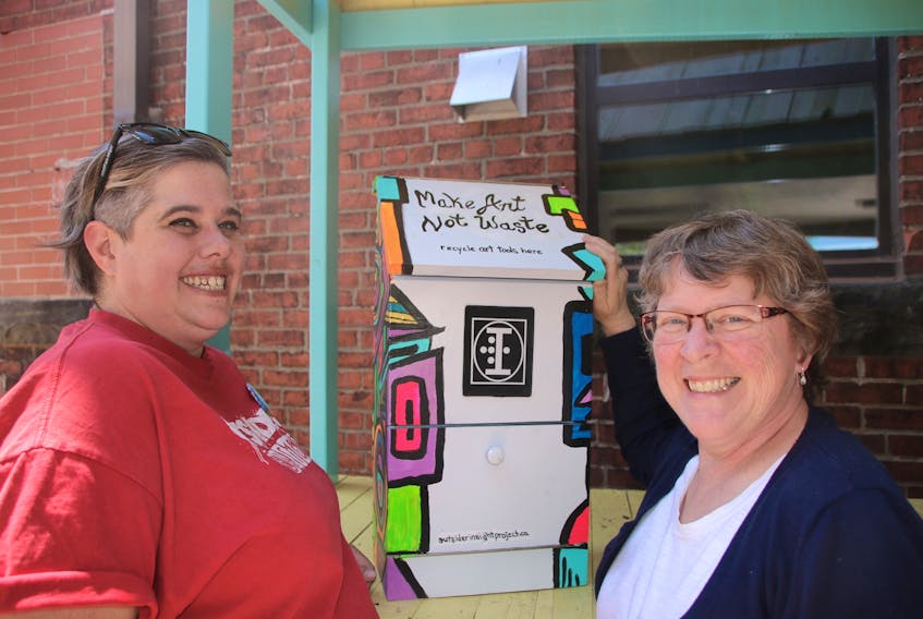 Jolene Reid, community volunteer, left, and Margaret Congdon, manager of the Truro Farmers’ Market, have set up a box at the market to collect art supplies. The supplies will be used to help with mental health efforts.