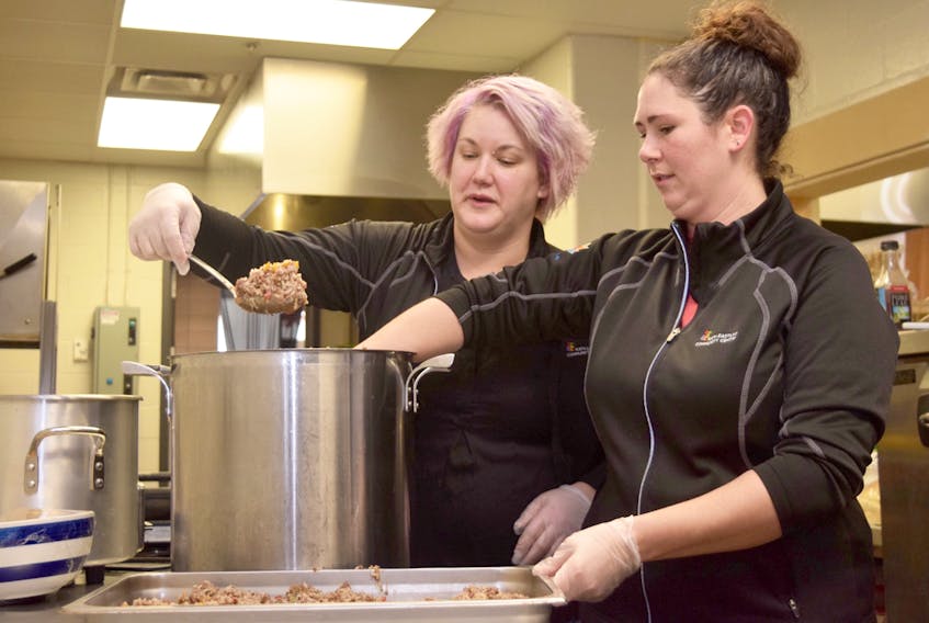 Preparing meals for the six international hockey teams participating in the World Junior A Challenge takes a lot of preparation and effort, often leading to full days in the kitchen. Michele Parker, right, and Jennifer Lamrock prepare a tray of beef and rice for a team meal Friday morning at the Rath-Eastlink Community Centre. Cody McEachern/Truro Daily News