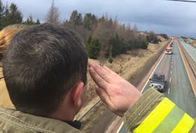Firefighter Jason McRae salutes the convoy bearing Skyler Blackie’s remains as it passes under the Onslow Road bridge on its way back to Truro.
