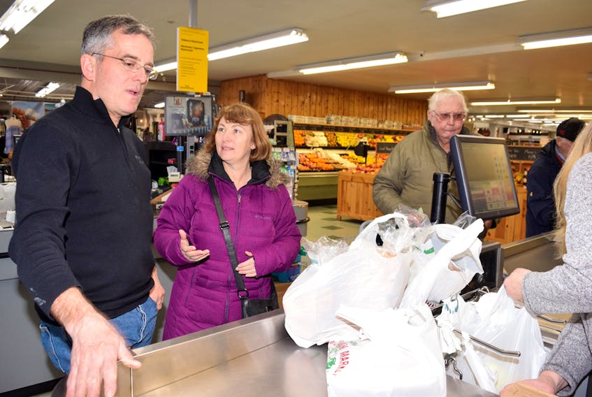 Laurie Jennings, at left, owner of the Masstown Market, chats with customer Karen Drysdale about the issue of banning single-use plastic grocery bags.