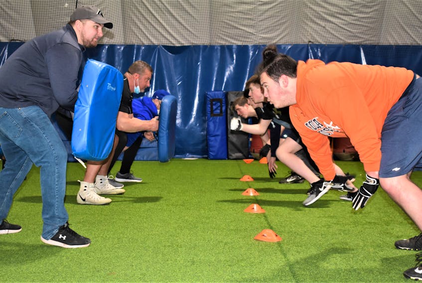 Canaan Hebb (right) starts to explode out of his stance in a lineman drill during the recent football camp held at the Cougar Dome. The former CEC player said he appreciated the many experienced coaches who were on-hand to pass along their knowledge.
