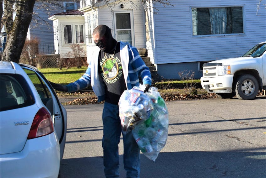 Subway Bottle Exchange worker/sorter Wendell Henderson grabs a bag of plastic bottles as well as a bag of cans, which are being donated to the Christmas Index program through a combined initiative from local organization Colchester Adult Learning Association (CALA) and business Colchester Signs and Promos. People can drop off their refundable bottles at the Bible Hill business to support program until Dec. 10.