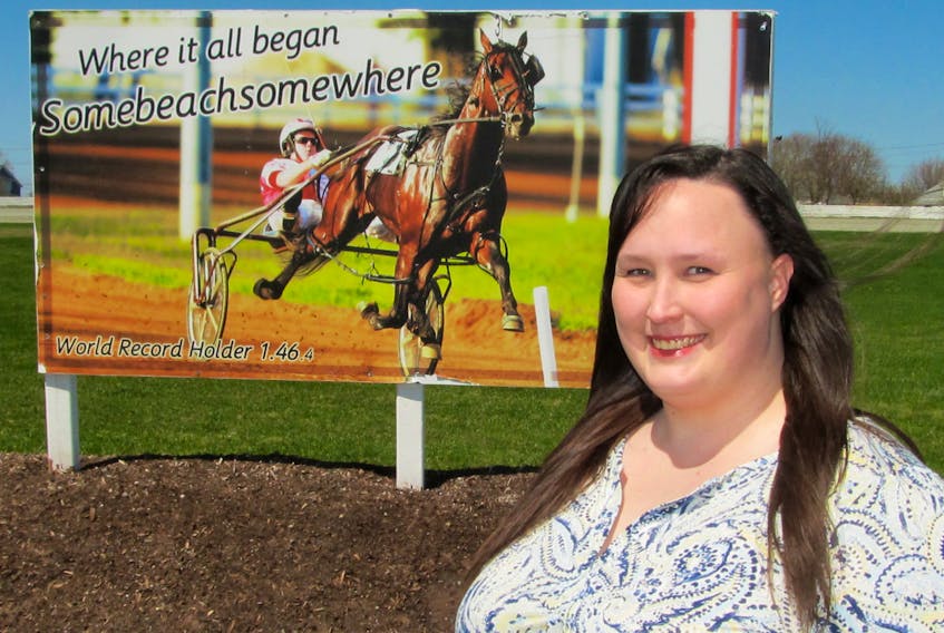 Daphne Cooper is shown at Truro Raceway’s centre field in front of world champion somebeachsomewhere sign.