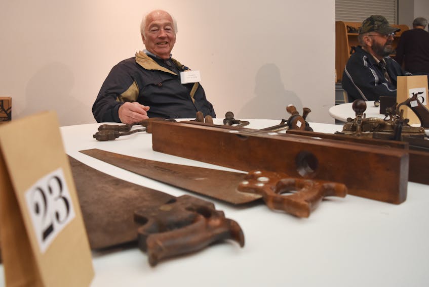 Garry Leliever sits at a table with portion of his collection of tools.