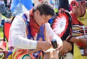 Paskwa Lightning, left, from Maskwacis in Alberta painstakingly fastened together a leather belt at the Millbrook First Nation Competition Powwow on Aug. 10 as his friend Stephane Mapachee from Pikogan, Quebec, looked on. Lightning says the finished belt will sell for about $400.