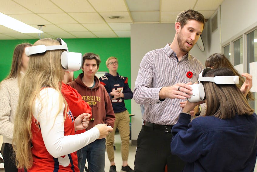 Tantramar Regional High School teacher Matt Wheaton shows students Anna Crossman, left, and Eka Gates how to use the new virtual reality headsets during an event earlier this month that celebrated the school receiving the Atlantic Innovative Educator Award, which comes with an $18,000 prize.