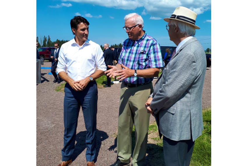 Cumberland-Colchester MP Bill Casey (centre) talks to Prime Minister Justin Trudeau and genealogist Stephen White from the University of Moncton at Beaubassin on Monday. White presented the prime minister a copy of the baptismal record of a Trudeau ancestor.