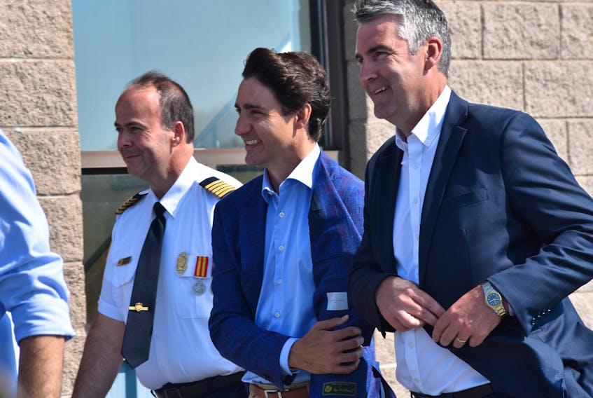 Barney's River Fire Chief Joe MacDonald walks with Prime Minister Justin Trudeau and Premier Stephen McNeil.