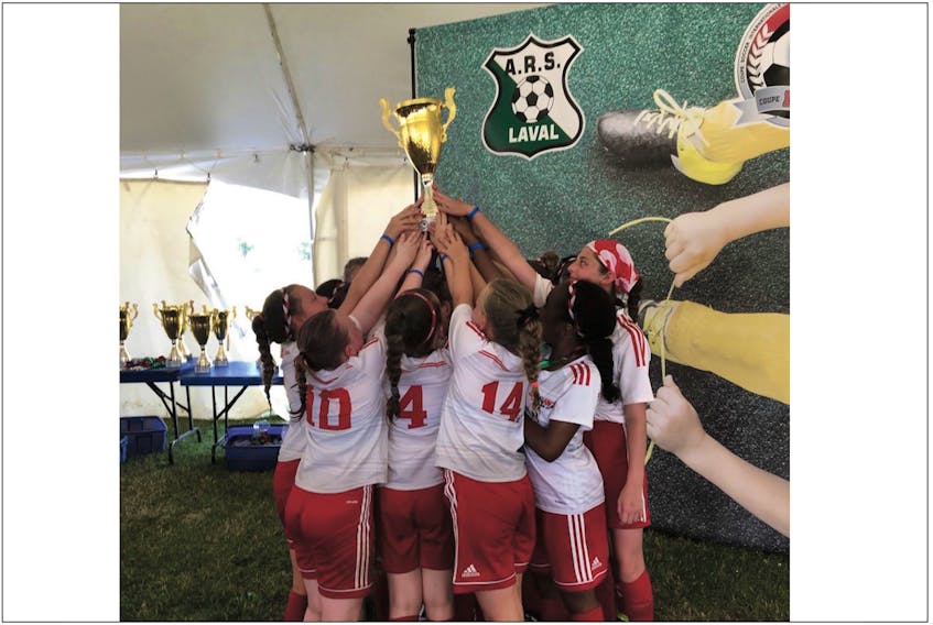 Members of the St. John’s Minor Association girls under-12 team hoists the championship trophy after claiming the title in their division Sunday at the Laval International Cup soccer tourney in Laval, Que. — Submitted/Scott Betts