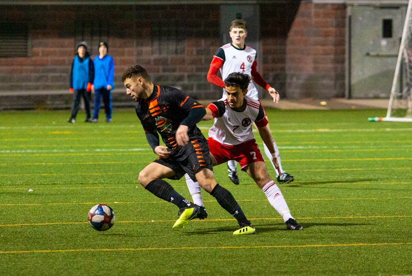 Marcus Campanile of the Cape Breton Capers, left, controls the ball as he’s pressured by Mario Maldonado of the New Brunswick Reds during Atlantic University Sport men’s soccer action at BMO Field in Fredericton on Friday. JAMES WEST/UNB ATHLETICS