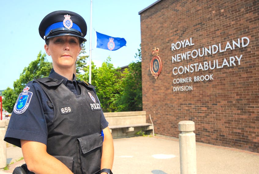 Const. Shawna Park poses for a photo outside the Royal Newfoundland Constabulary headquarters in Corner Brook, with a flag flying at half-mast in honour of two officers slain in the line of duty in New Brunswick last week.