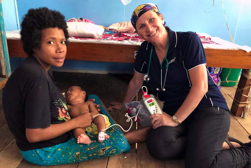 Retired nurse Juanita Jacobs of Corner Brook with the mother of an ill child she helped during her recent humanitarian volunteer mission to Papua-New Guinea.