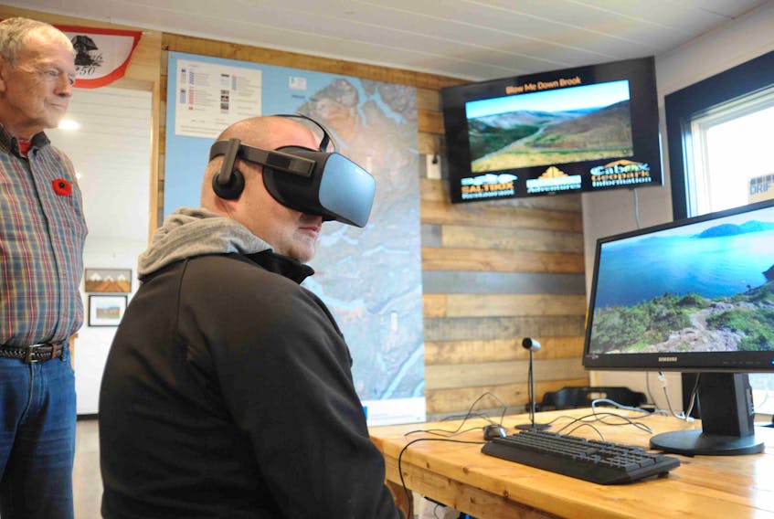 Daniel Gillis, seated, checks out a virtual reality tour of some of the highlighted locations around the Bay of Islands during his visit to the new Cabox Geopark Information Centre in Humber Arm South. Standing to his left is Arne Helgeland.
