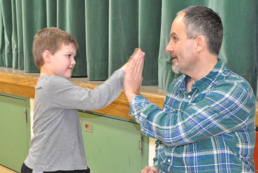 Kindergarten student Nolan Fry gives a high-five to Gerald Morgan, his principal at Stephenville Primary School, after having a few words to say about him during a surprise assembly in Morgan’s honour on Tuesday, when it was announced he is one of Canada’s outstanding principals.