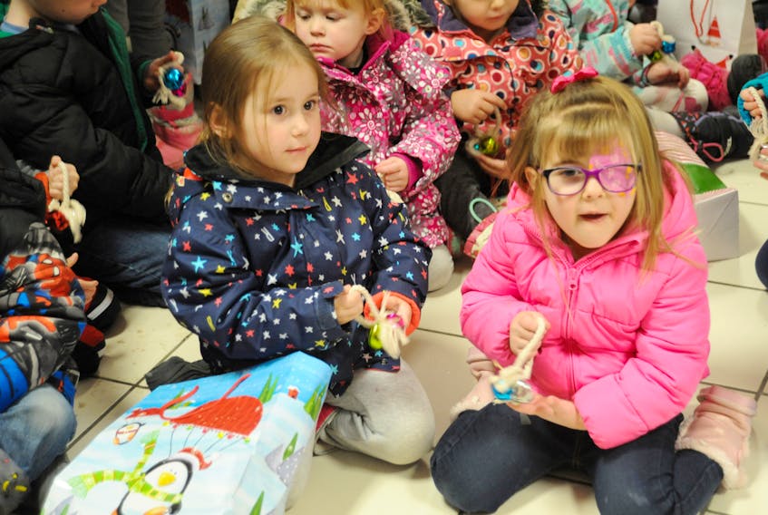 Three-year-olds Lexi Sullivan, left, and MacKenzie Terry sing carols and ring jingle bells they and other kids from Stepping Stones Day Care brought to the opening of the Gingerbread House at the Valley Mall in Corner Brook Friday morning. This is the 37th year for the project — co-sponsored by the mall, the Salvation Army and VOCM — that accepts donated gifts to be distributed to needy families during the Christmas season. Last year, around 2,700 gifts were dropped off at the Gingerbread House structure located on the mall’s lower level.