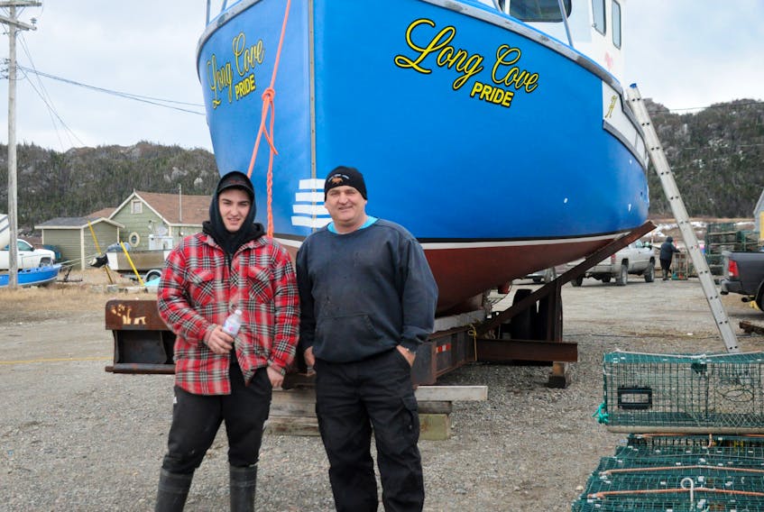 Chad Hickey, left, and his dad Renny Hickey pose for a photo in front of their boat Long Cove Pride.