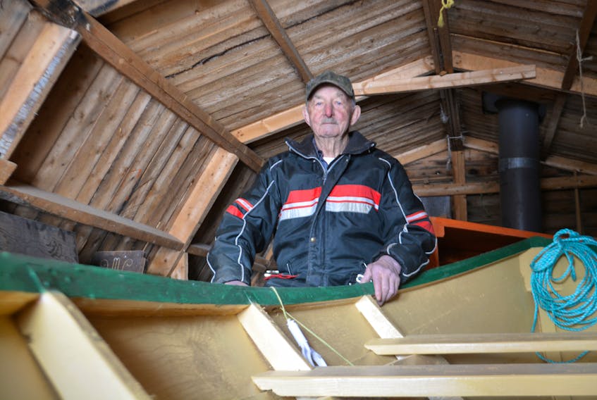 Roy Dennis of John's Beach sits next to the latest and possibly last boat he will ever finish. In his lifetime, he figures he has built more than 100 vessels.