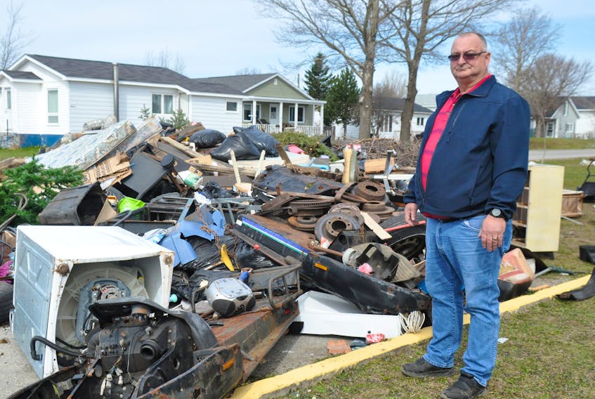 Henry Hedderson, president of the Stephenville Lions Club, poses 
next to the ever-increasing amount of debris dumped on the Lions Club property on Woodland Street.