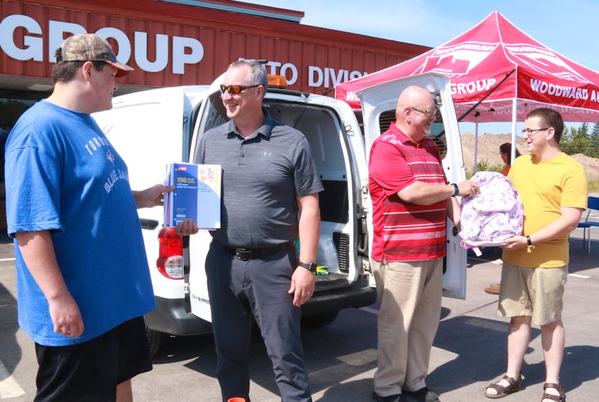 Perry Compton (second from left) from Woodward Motors accepts a donation from Austin Curlew while Desmond Fudge (second from right) passes a donation to Brian Snow (far right) from the Deer Lake Salvation Army community services.