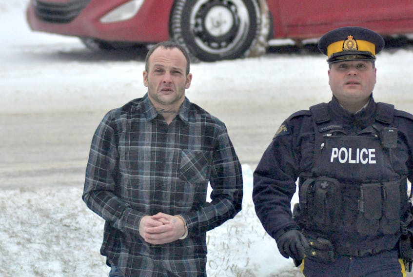 Matthew Delaney is led into provincial court in Stephenville by a police officer on Friday morning.