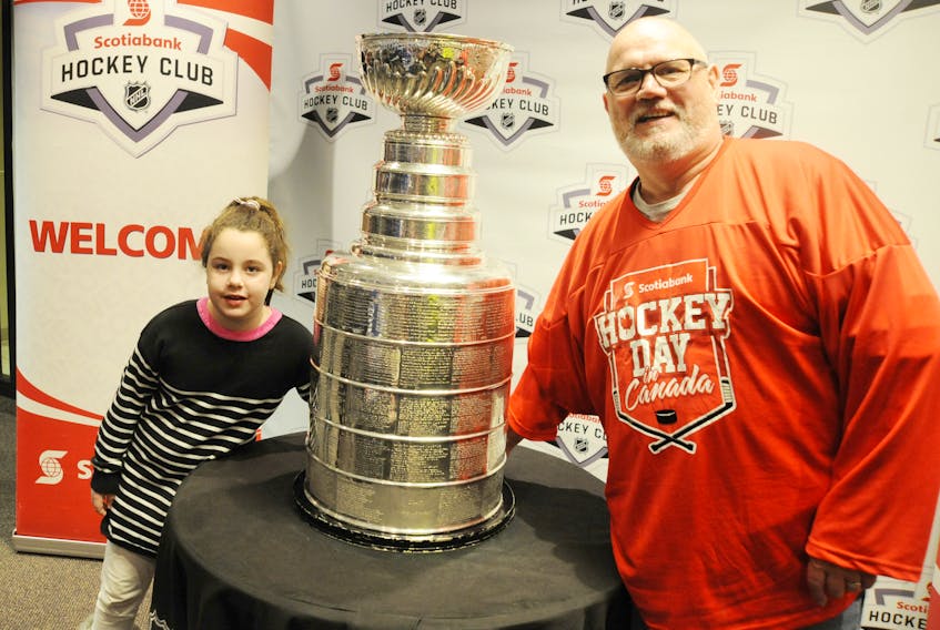 Bob Bennett, winner of The Western Star’s Hockey Day in Canada prize pack promotional contest, and his daughter Sophie, 6, get their photo taken with the Stanley Cup after taking in the hockey celebration’s breakfast event Friday morning.
