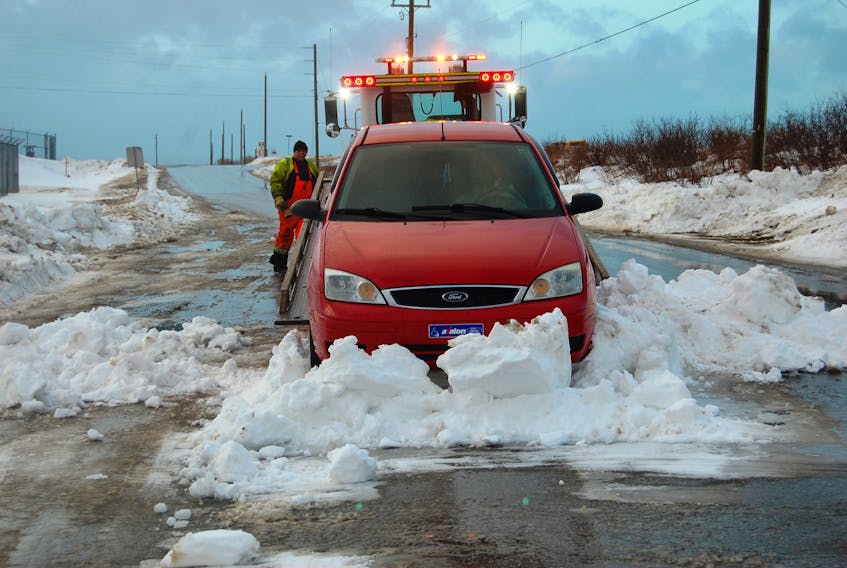 Dave Slade of Eddy Services Towing and Transport works at removing a car from a snow bank on Massachusetts Drive in Stephenville, one of two vehicles that got stuck in the location during Thursday night’s storm.
