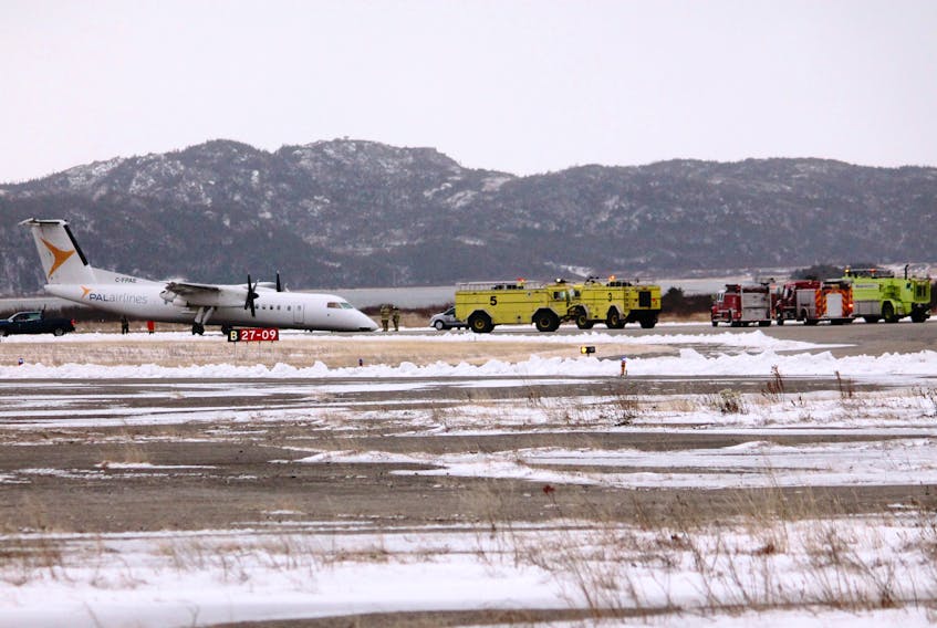 Emergency vehicles are seen near the Provincial Airlines plane that was nose down at the Stephenville airport runway after making an emergency landing at noon hour with 50 passengers on board.