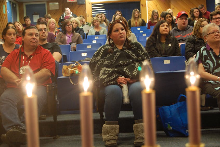 Those in attendance at the Day of Remembrance and Action on Violence Against Women listen in as Janice Kennedy, executive director of the Bay St. George Status of Women, speaks with candles in memory of the 14 women killed at at L'Ecole Polytechnique in Montreal 28 years ago lit in the foreground.