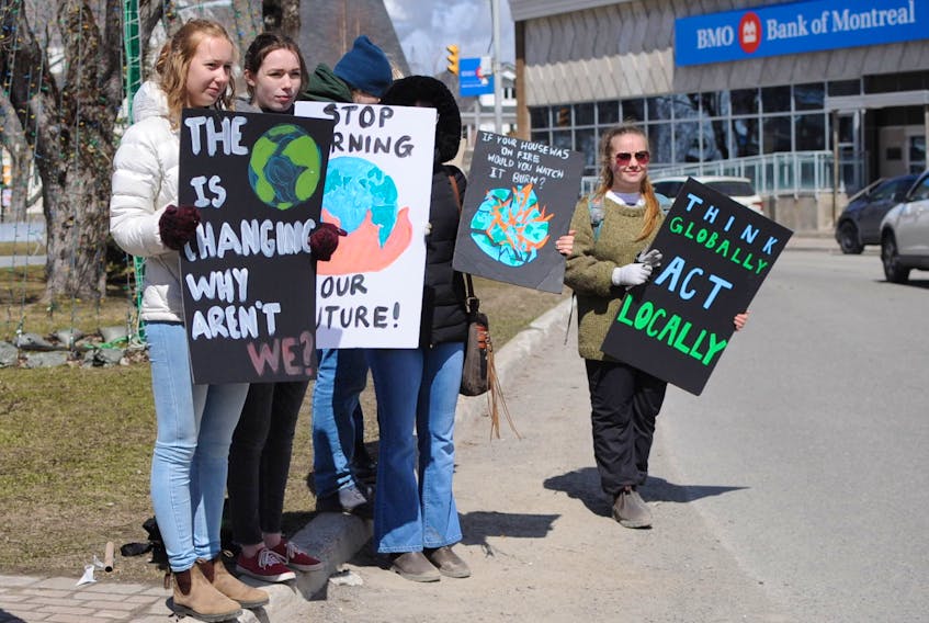 Students hold signs as they participate in a climate strike on West Street in downtown Corner Brook Friday.