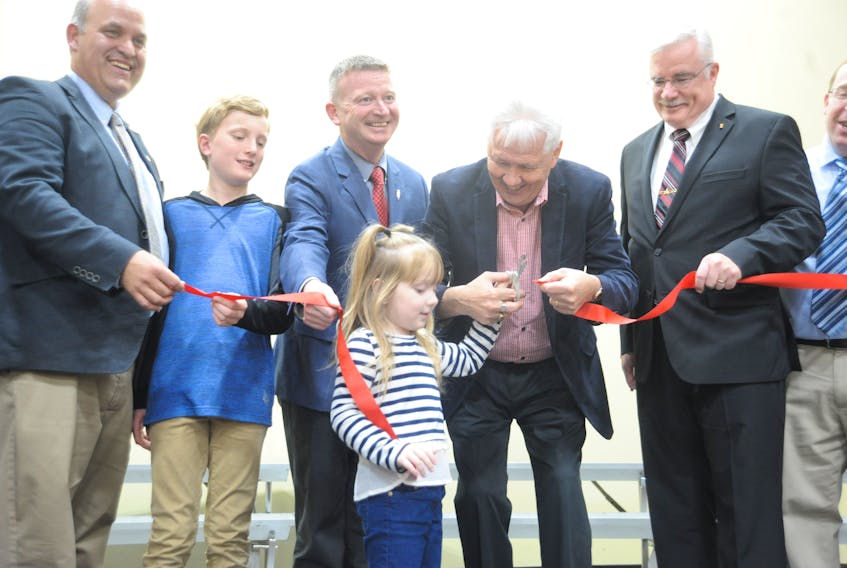 Municipal Affairs and Environment Minister Eddie Joyce, second from right, had some help from kindergarten student Jae-Ana Watkins, the youngest student at Eastside Elementary School, in cutting the ribbon to officially open the Corner Brook school Friday. Also on hand were, from left, principal Robert Matthews, Grade 6 student Markus Spingle — the school’s oldest student, Education and Early Childhood Development Minister Dale Kirby, and Tony Stack, chief executive officer of the Newfoundland and Labrador English School District