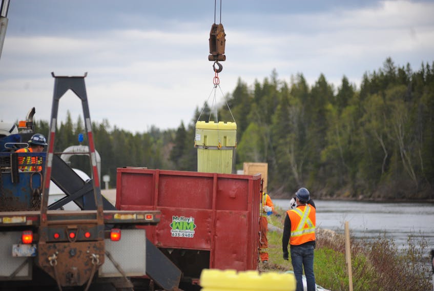 One of the 55 barrels removed from the Deer Lake Canal in protective containers is lowered into a dumpster for analysis and proper disposal Tuesday.