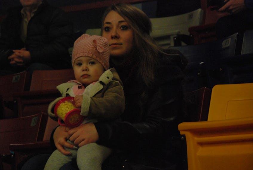Corner Brook native Kayla Park and her one-year-old daughter Priarrose Park take in the action during their first Corner Brook Royals game Friday night at the Corner Brook Civic Centre.