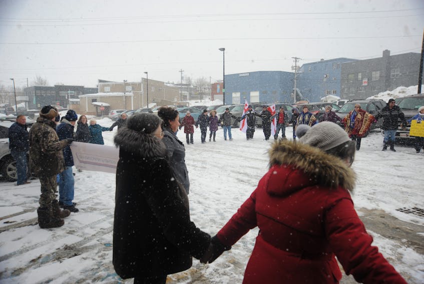 Participants in the rally against the Qalipu Mi'kmaq First Nation Band enrolment process hold hands and sing in a circle to close out the event in Corner Brook Saturday.