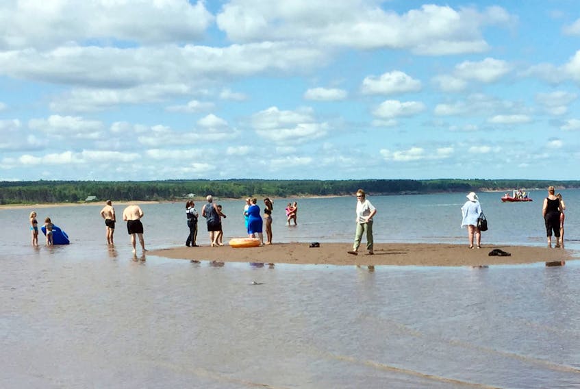 People stand on a sand bar at Blue Sea Beach after a pair of five-year-old girls were brought to shore by members of the Wallace Fire Department. Two pair were on two floaties that were blown offshore by the wind. Lisa Betts photo