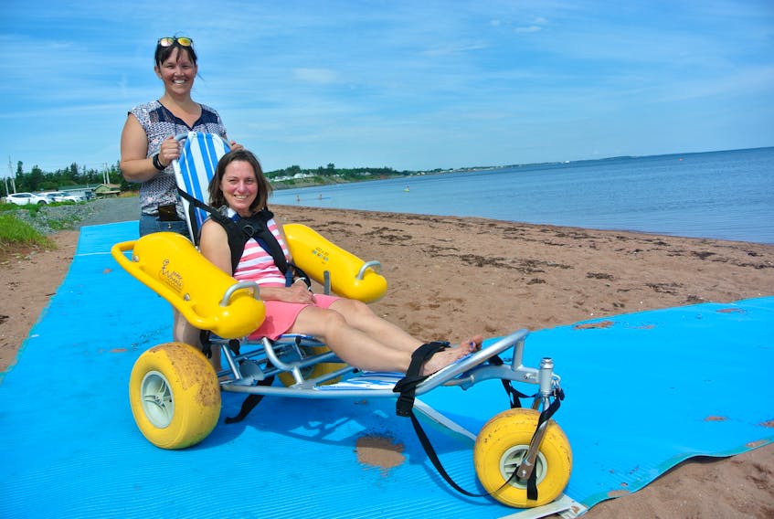 Cumberland health boards co-ordinator Colleen Dowe (seated) and the Municipality of Cumberland’s recreation and physical activities co-ordinator Vicki Weaver demonstrate the new accessibility mat and WaterWheels floating wheelchair that’s now available at Heather Beach Provincial Park near Port Howe.