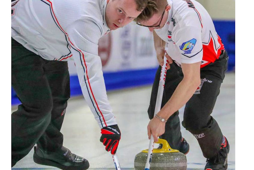 Canada’s Matthew Hall, left, and Sterling Middleton sweep a rock during a game against Marco Hiesli of Switzerland at the World Junior Curling Championships in Liverpool on Monday. Canada, skipped by Tyler Tardi, won 8-3.