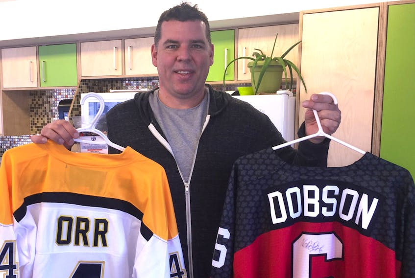 Adam Binkley holds an autographed Bobby Orr jersey and an autographed, game worn Noah Dobson jersey. Both are available through the Boys and Girls Club of Summerside's online auction on their website. -Ethan Paquet photo