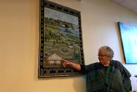 Mary Anne Mehaffey points to the image of Yarmouth Heights on the mat she made that hangs on a wall near the entrance at Yarmouth Heights, where she lives.