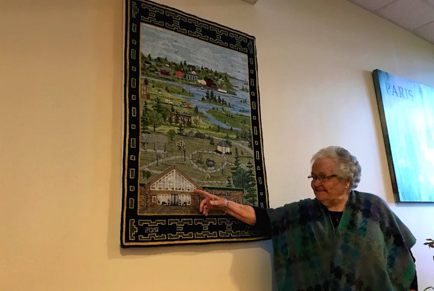 Mary Anne Mehaffey points to the image of Yarmouth Heights on the mat she made that hangs on a wall near the entrance at Yarmouth Heights, where she lives.