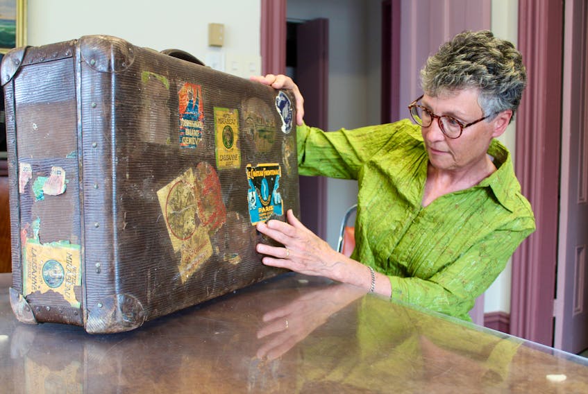 Chris Bolger checks out the much-travelled suitcase that belonged to Sara Corning. Bolger has written a play about Corning that will be presented at Yarmouth North Baptist Church Sept. 13. The suitcase, which bears travel stickers from places Corning travelled to or through, is in storage at the Yarmouth County Museum. ERIC BOURQUE