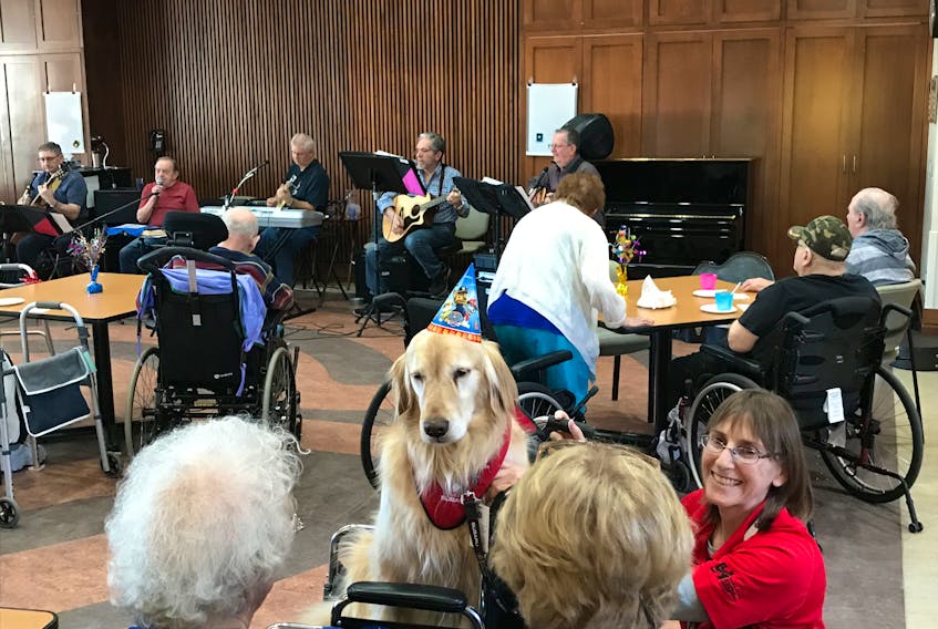 Pre-Covid photo of Wendy Vickers kneeling with therapy dog Jeni, who is wearing a party-hat for a happy occasion.
Morgan Leary Photo