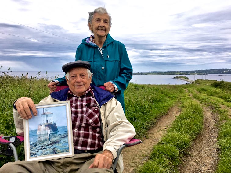 The 62-year bride and groom – Robert and Ethel Cottreau - with Bug Light in the far background. Robert is holding a photo of his family’s home on Bug Light that existed there until 1959.